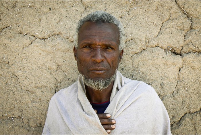 Portrait of an old man in front of a wall - find a fixer for better travel photography