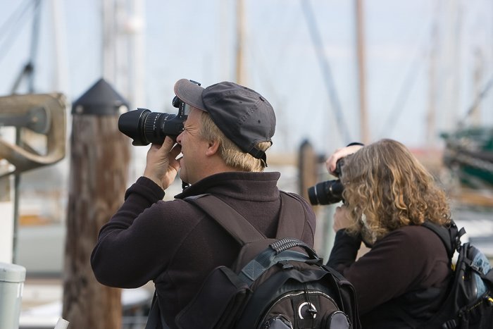 Man and woman at a pier with DSLRs taking photos
